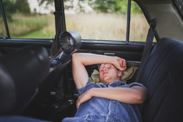 Person napping in the back seat of a car.