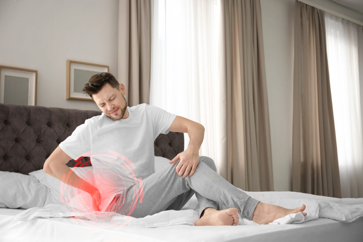 Man sitting up in bed with back pain.